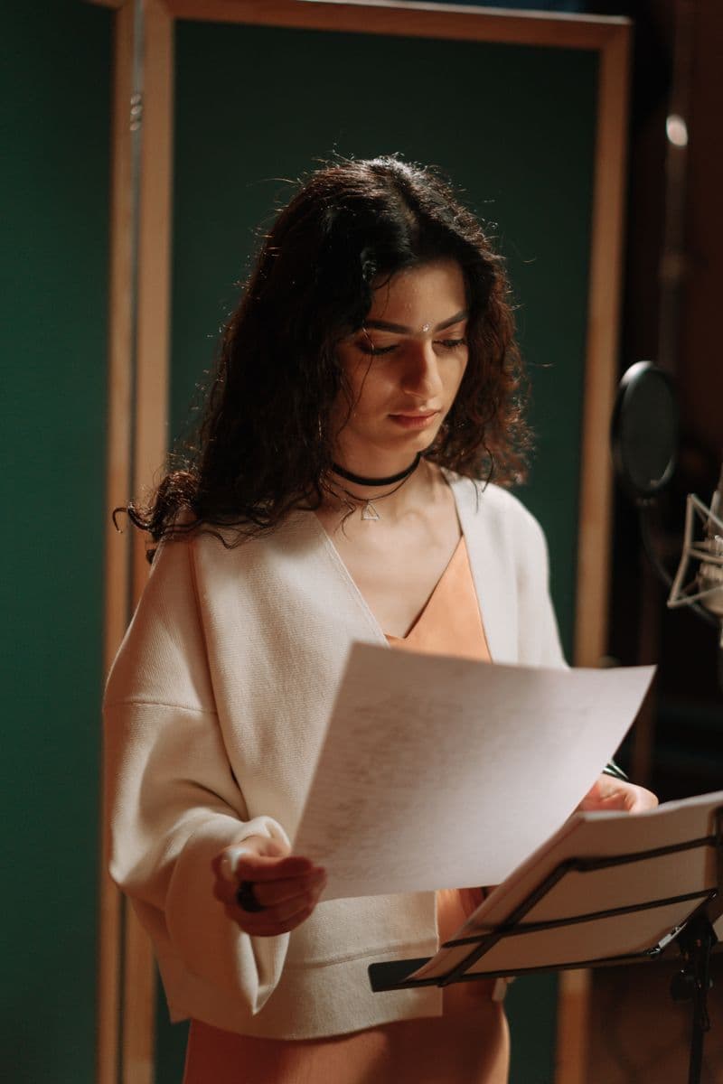 Maren Solano in a recording booth, reading lyrics at the mic